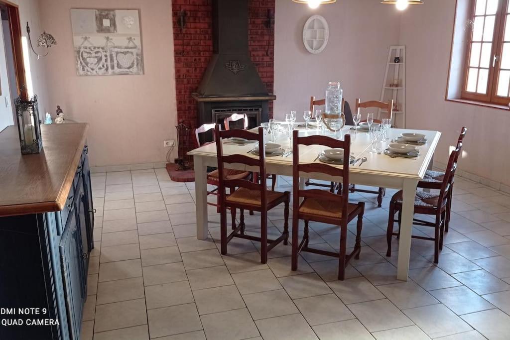 a dining room with a table with chairs and a stove at Maison de ferme au calme jusqu'à 10 personnes in Gannay-sur-Loire