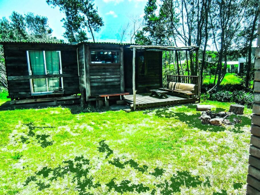 una cabaña en un patio con césped verde en Cabaña en el Bosque de la Viuda, en Punta del Diablo