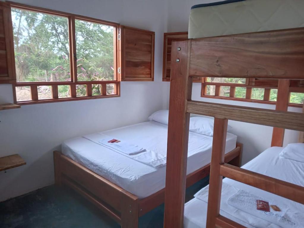 two bunk beds in a room with two windows at Cabaña Caporo - privada con ubicación central in Acanti