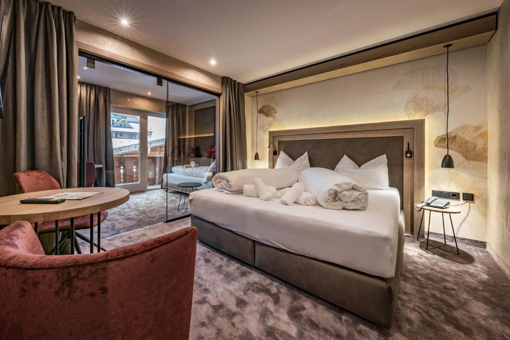 ein Schlafzimmer mit einem großen Bett, einem Tisch und Stühlen in der Unterkunft Hotel Gasthof Brücke in Mayrhofen