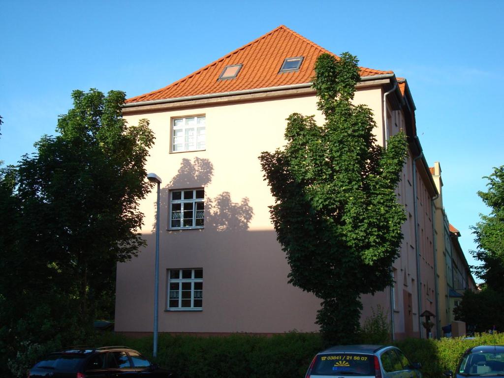 a white building with a tree in front of it at Ferienwohnung Henny in Wismar