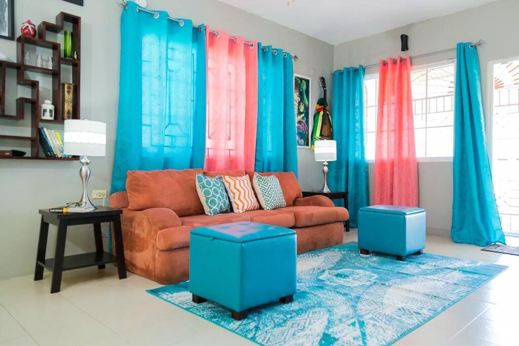 a living room with a brown couch and blue curtains at Hellshire Portmore Vacation Home in Portmore