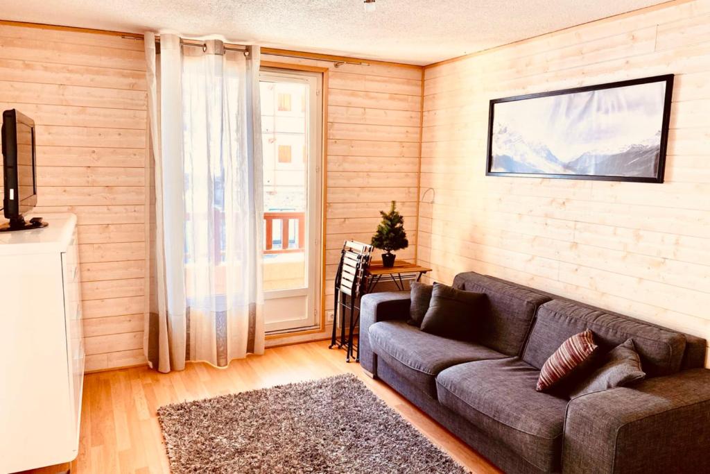 a living room with a couch and a window at 2 room apartment 200m from the slopes In the heart of the ski resort in Valberg
