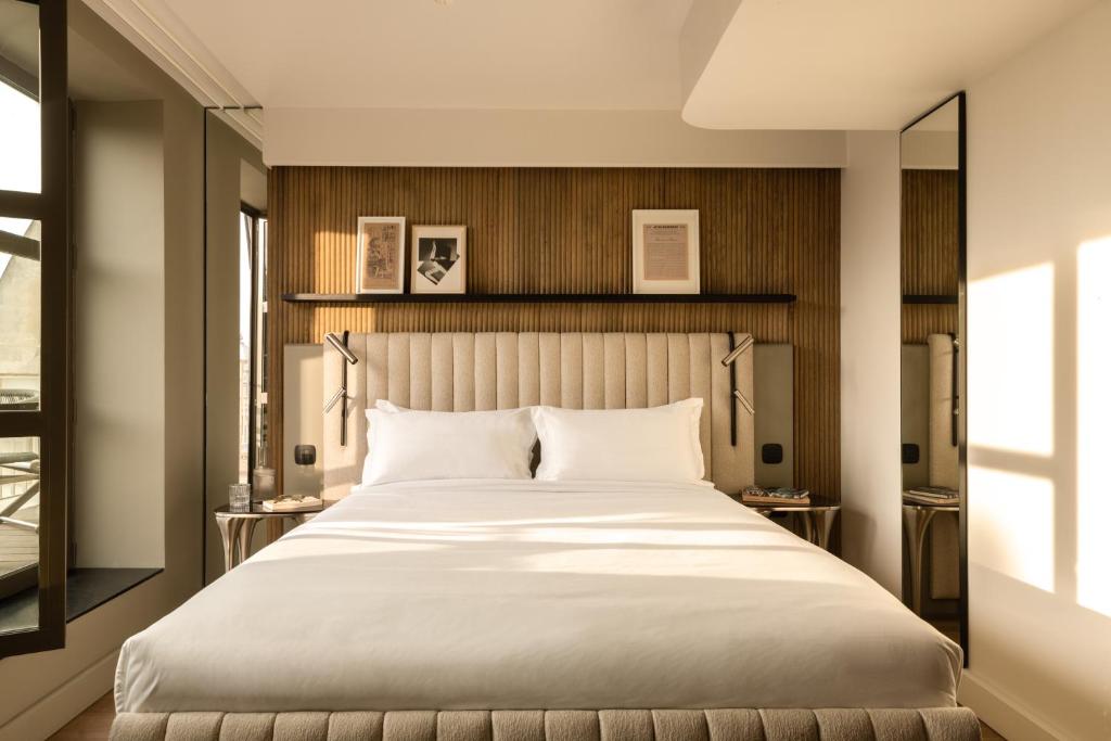 a bedroom with a large white bed and a window at Hôtel Dame des Arts in Paris