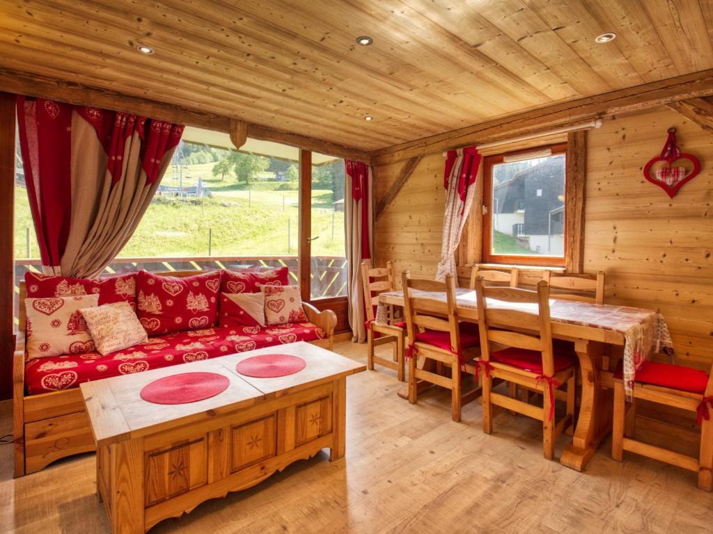 - un salon en rondins avec un canapé rouge et une table dans l'établissement Appartement cosy à Morillon 1100, balcon sud, 2 chambres, 6 pers. - FR-1-642-18, à Morillon