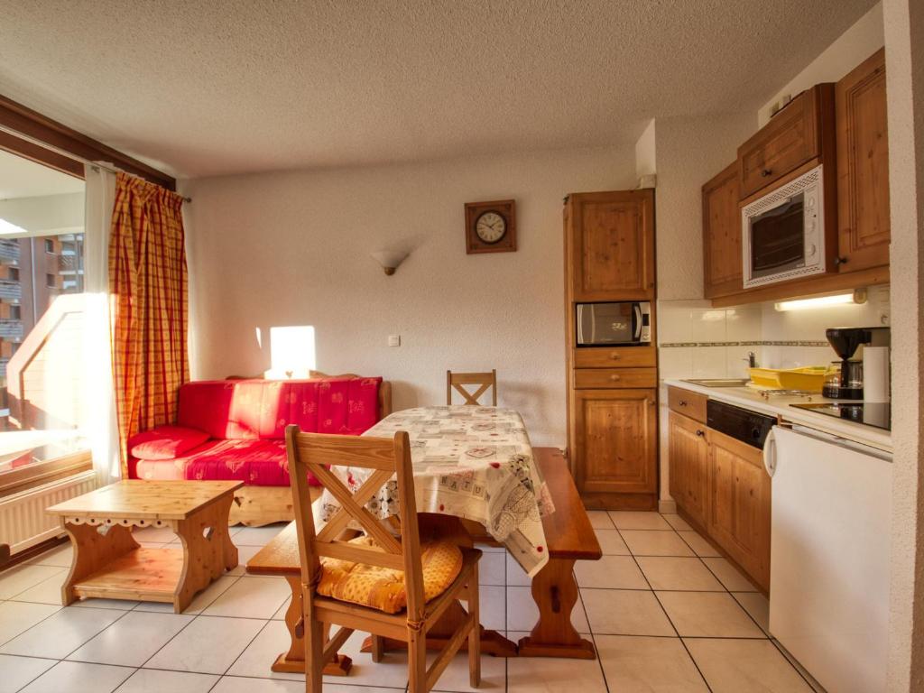 une cuisine avec une table et un canapé rouge dans l'établissement Appartement pour 6 pers. au pied des pistes à Morillon 1100, proche jardin d'enfants - FR-1-642-53, à Morillon