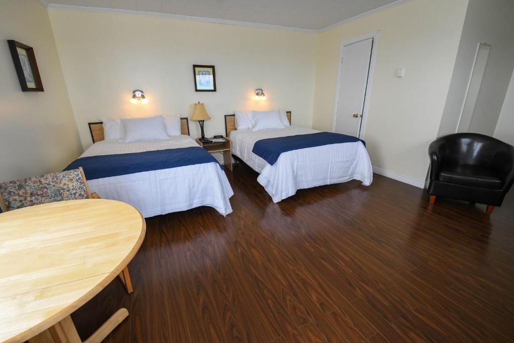een hotelkamer met 2 bedden en een tafel bij Motel Nouvel Horizon in Perce