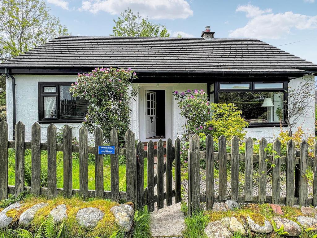 uma pequena casa branca com uma cerca de madeira em Glen Mhor em Glenelg