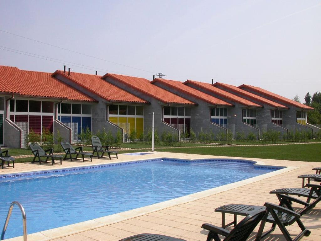 a resort with a swimming pool with chairs and a building at Apartamentos Turísticos Silvano Posada de Llanes in Posada de Llanes