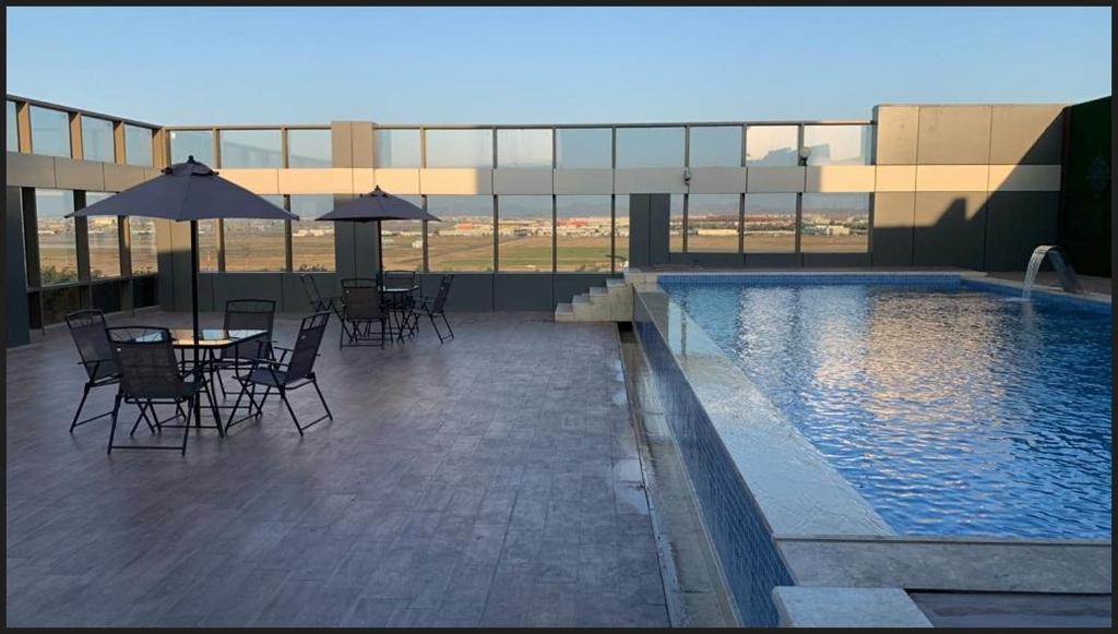 une terrasse avec des tables et des chaises ainsi qu'une piscine dans l'établissement Al Rayyan Tower, à Djeddah