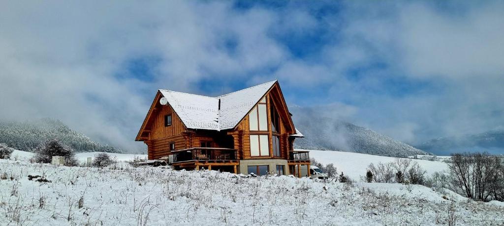 Cabaña de madera en la nieve con techo cubierto de nieve en Chalet Liptov, en Ižipovce