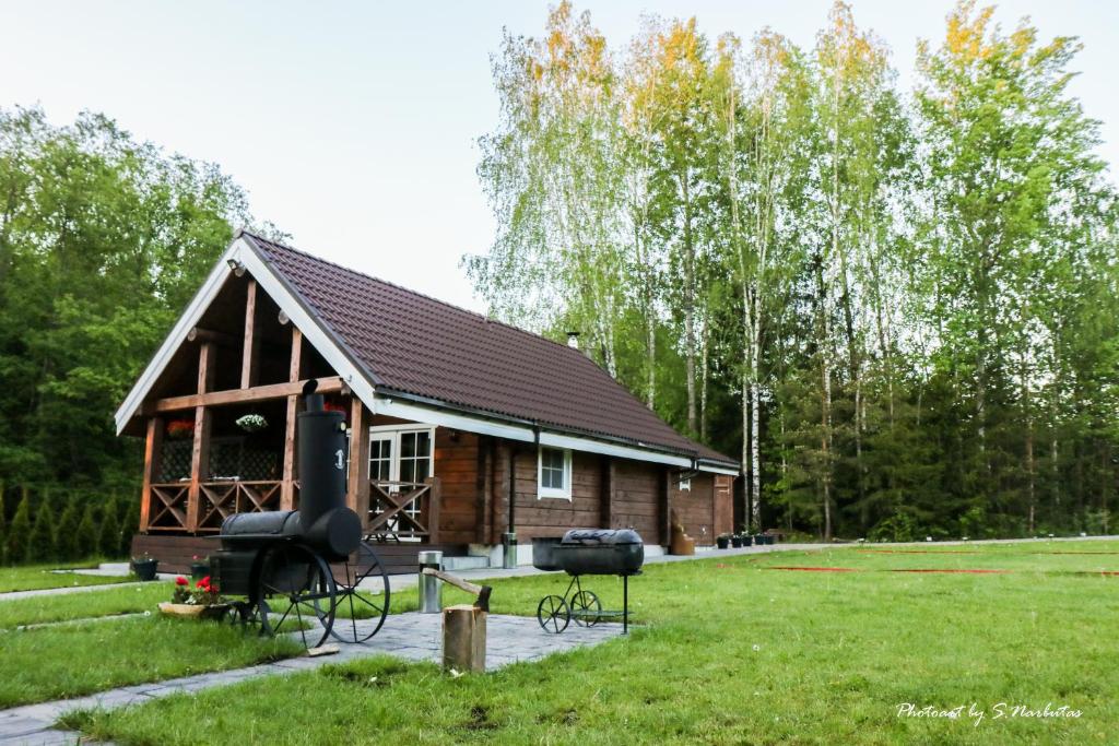a small log cabin with a grill in a yard at Sodybos Narūnas namelis dviems in Jonava