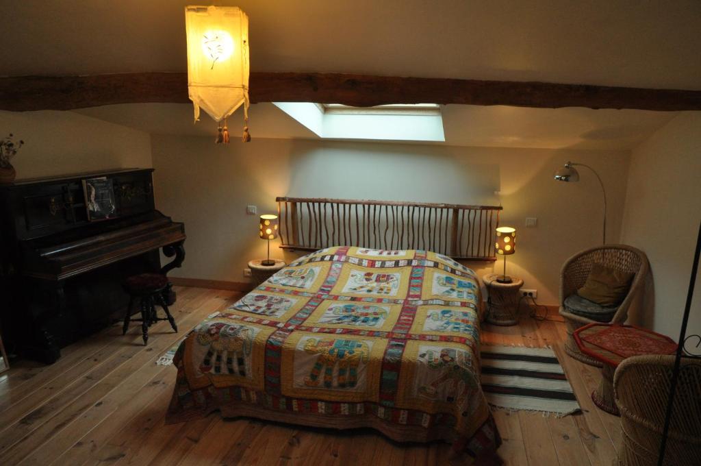a bedroom with a large bed and a piano at La Grange d'Agnès in Montmaur-en-Diois