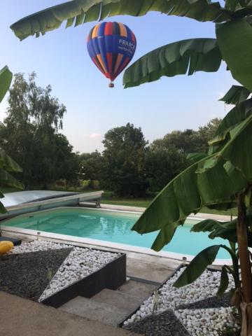 a hot air balloon flying over a swimming pool at La paillote idyllique in Faverolles-sur-Cher