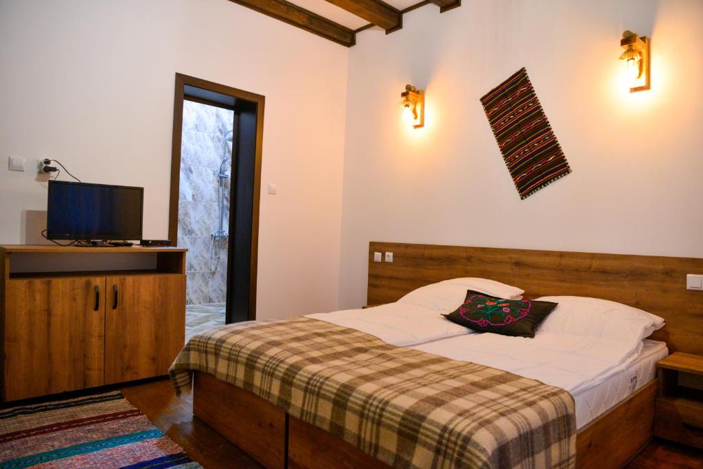 1 dormitorio con 1 cama y TV en la pared en Къщи за гости НЕСИ en Leshten