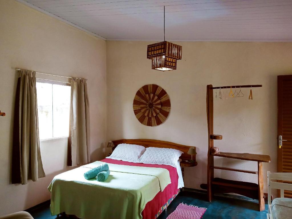 um quarto com uma cama, uma janela e um lustre em Villa Ágape - Chapada dos Veadeiros em Alto Paraíso de Goiás