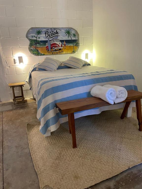 Una cama con una manta azul y blanca y un banco en La Bocana Surf House, en Santa María Huatulco