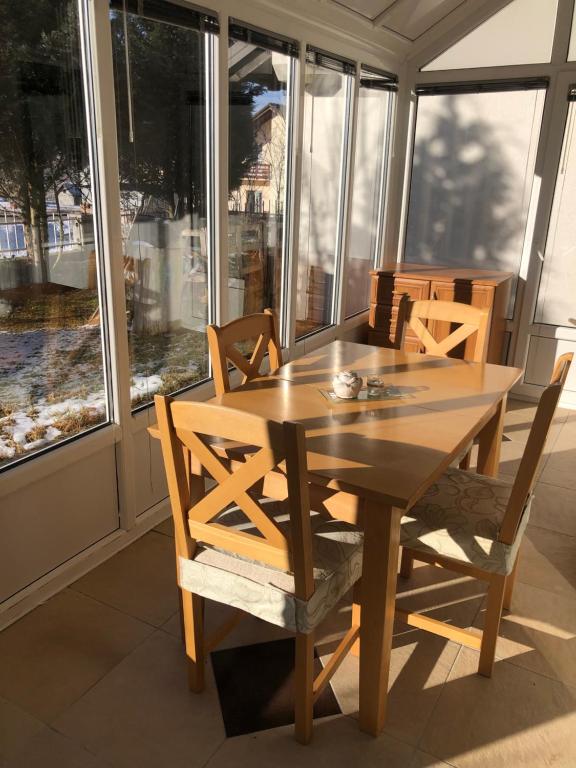 einen Holztisch und Stühle in einem Zimmer mit Fenstern in der Unterkunft Apartman Cypres in Kupres
