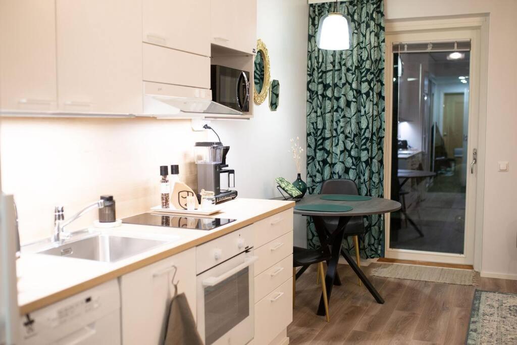 a kitchen with a sink and a table in it at New studio apartment with free parking in Kuopio