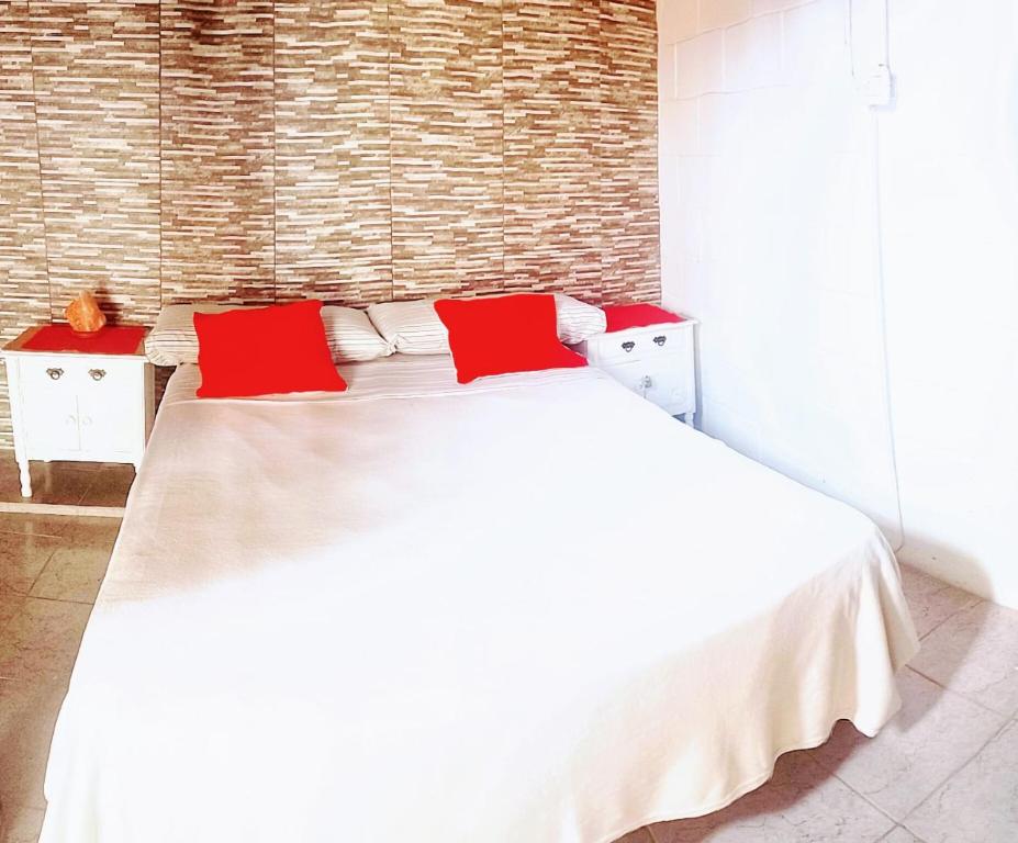 a bedroom with a white bed with red pillows at El Descanso in San Luis