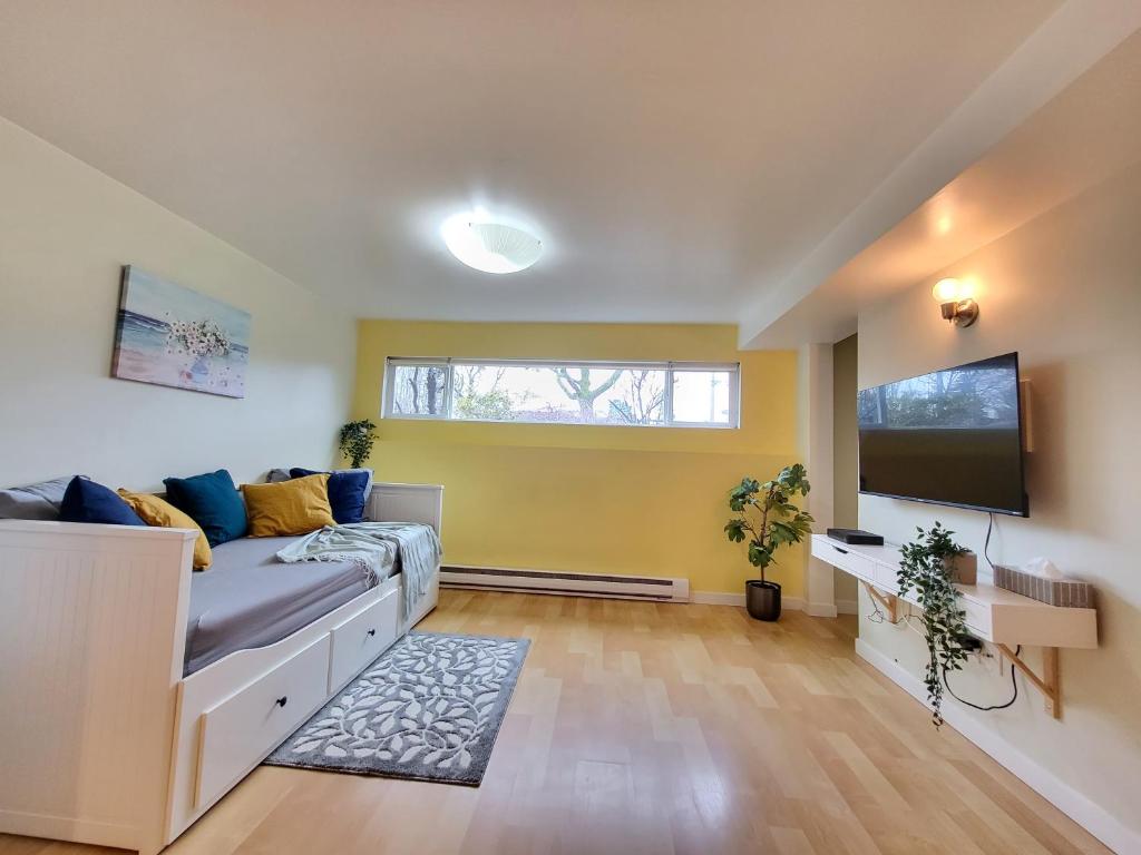 uma sala de estar com um sofá e uma televisão de ecrã plano em Sunshine Suite em Vancouver