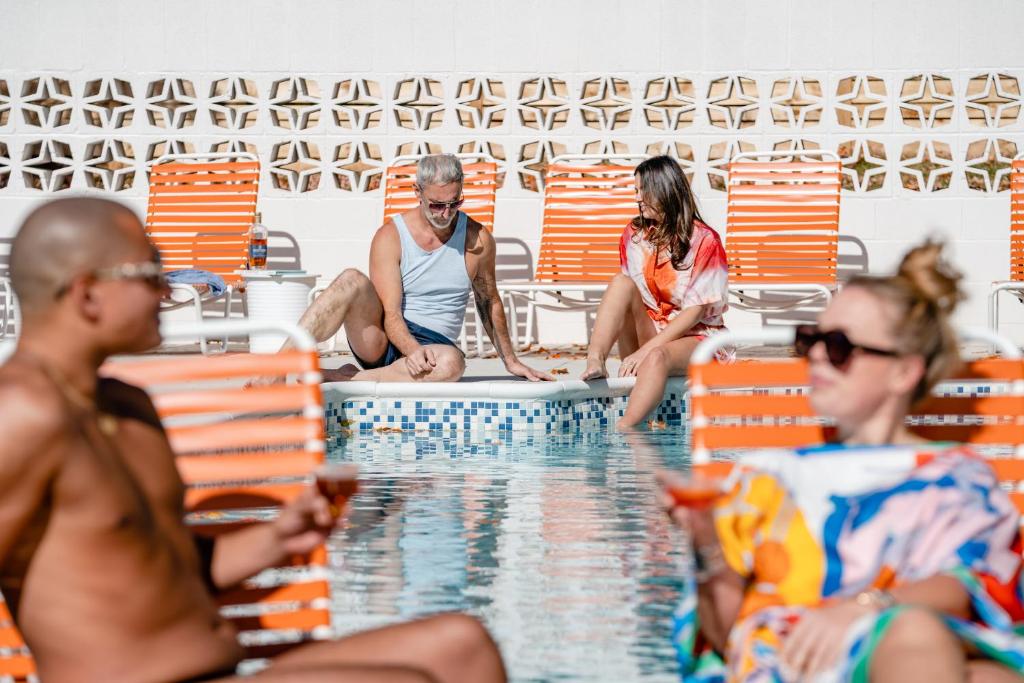 um grupo de pessoas sentadas ao redor de uma piscina em Bardstown Motor Lodge em Bardstown