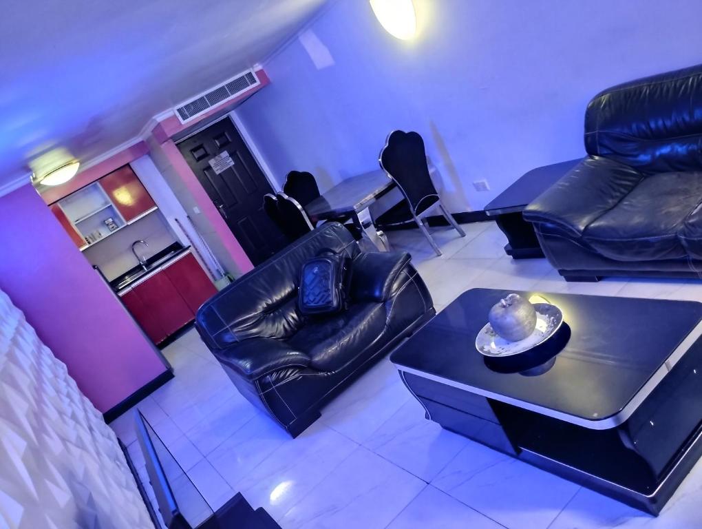 a living room with black leather chairs and a table at Festival mall apartments in Lagos