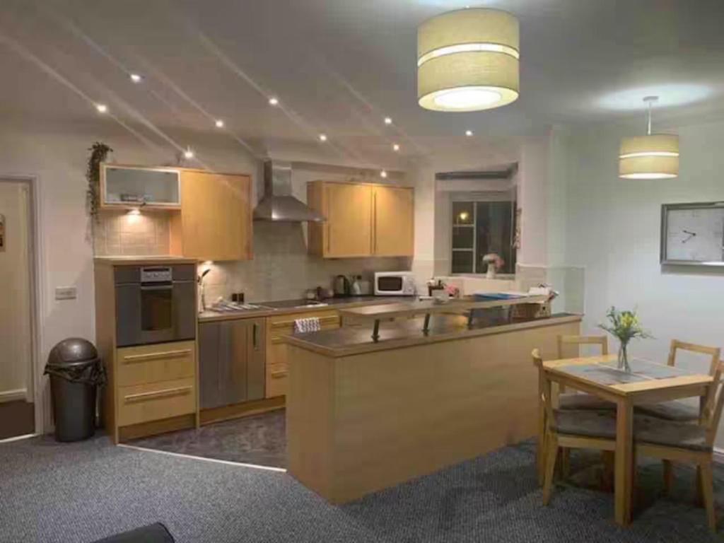 een grote keuken met houten kasten en een tafel bij Modern Apartment in Barry Waterfront in Barry