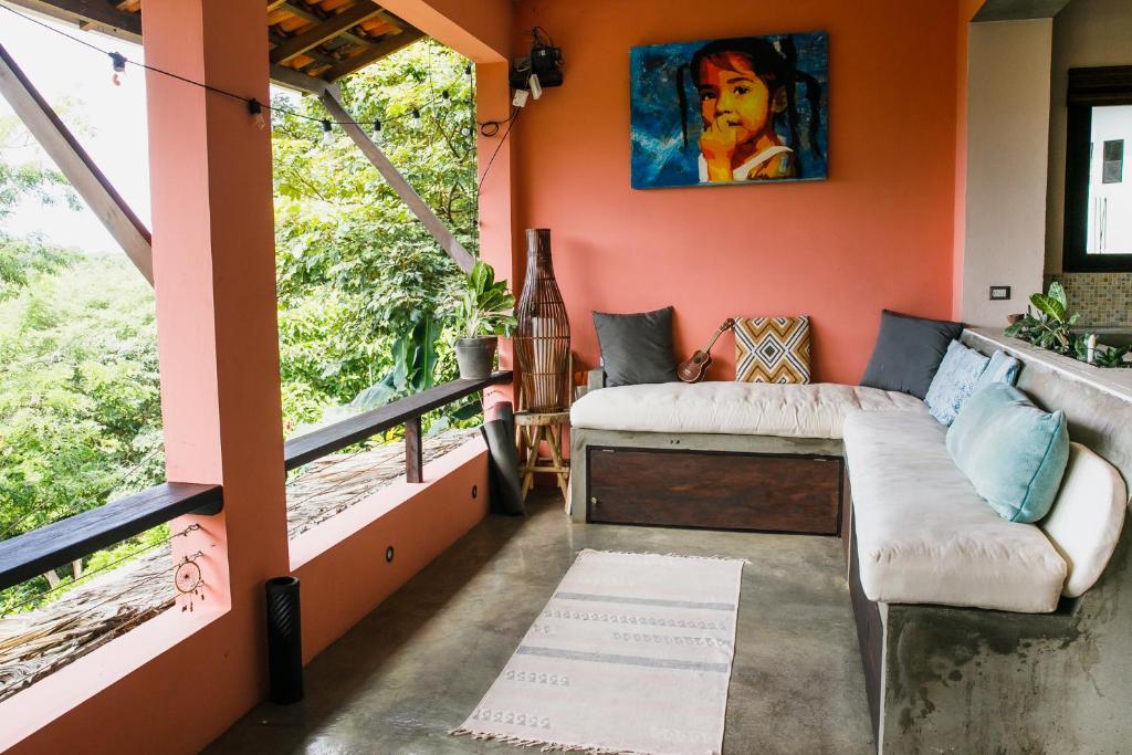 El PlantelにあるCasa Del Arte - rooms with private and shared bathroomsのオレンジ色の壁、ソファ、窓が備わる客室です。
