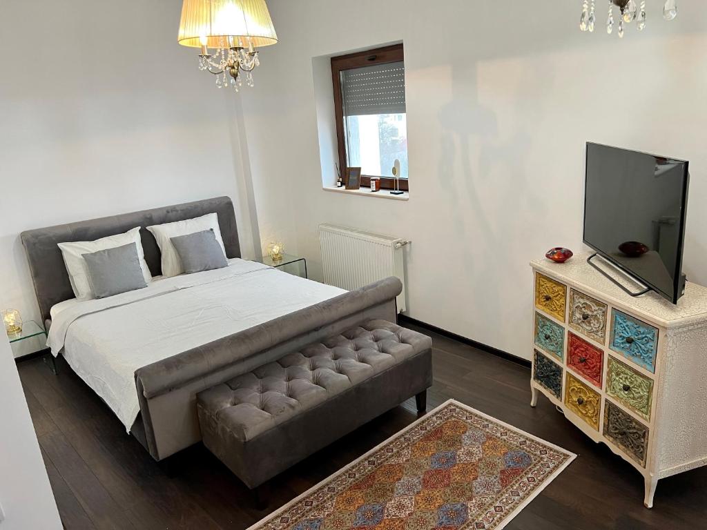 een slaapkamer met een bed, een bank en een tv bij AGO Studio in Boekarest