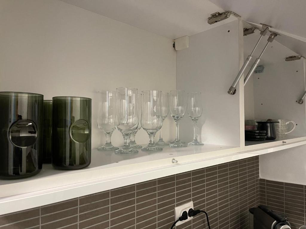 uma fila de copos de vinho sentados numa prateleira em Prestige Apartment Teslic II em Teslic