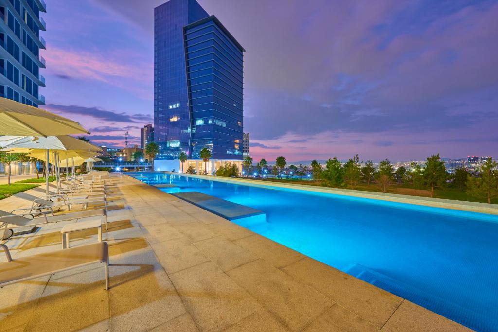 una piscina con tumbonas y un edificio alto en Park Life Querétaro en Querétaro