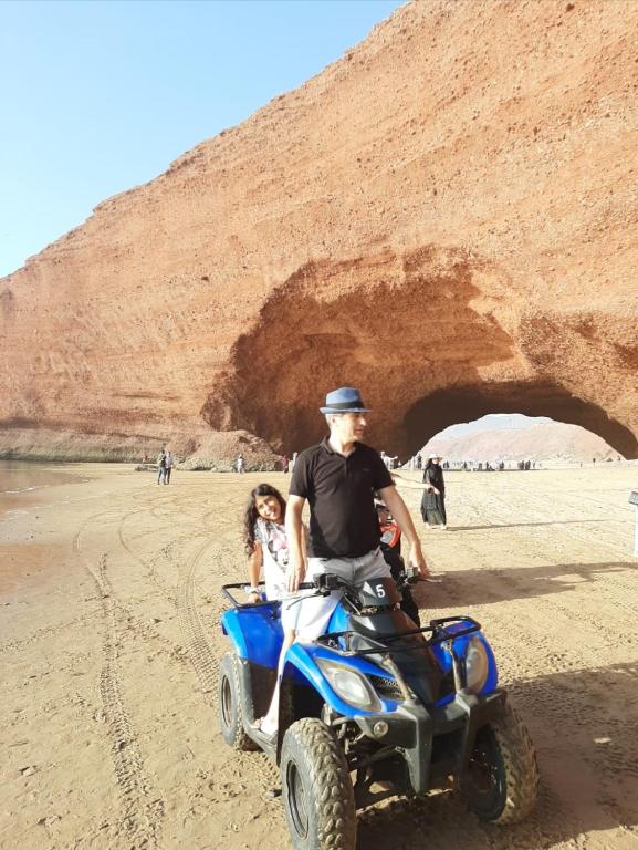 a man and a little girl riding a atv on the beach at Dar diafa samira in Mirleft