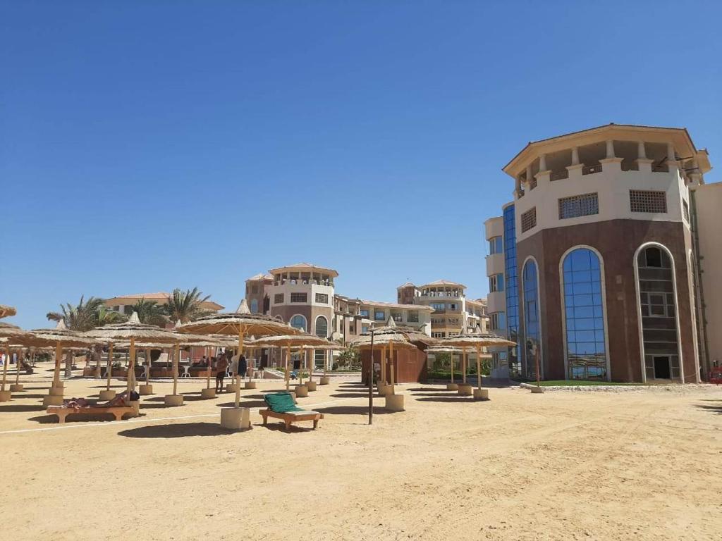 a beach with umbrellas and chairs and a building at Tony's Privy One bed by Red Sea in Hurghada