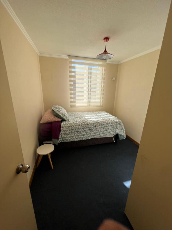 Habitación pequeña con cama y ventana en Arriendo departamento, en Temuco