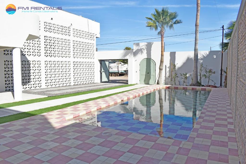 a pool in front of a white building with a palm tree at Casa Jaguar in Puerto Peñasco