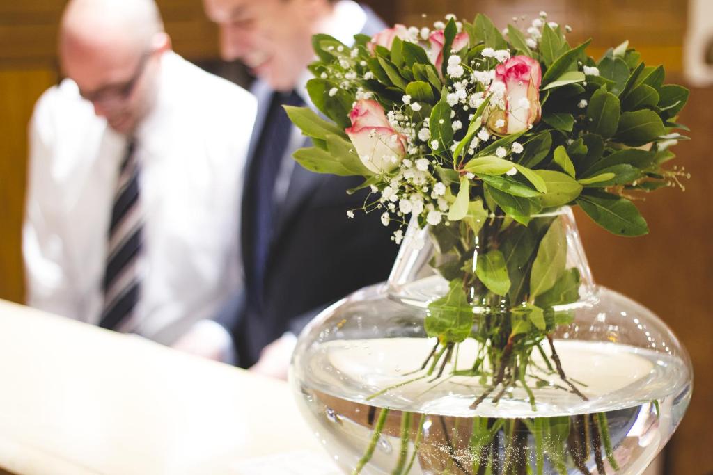 a vase filled with flowers on a table with a man at Zappion Hotel in Athens