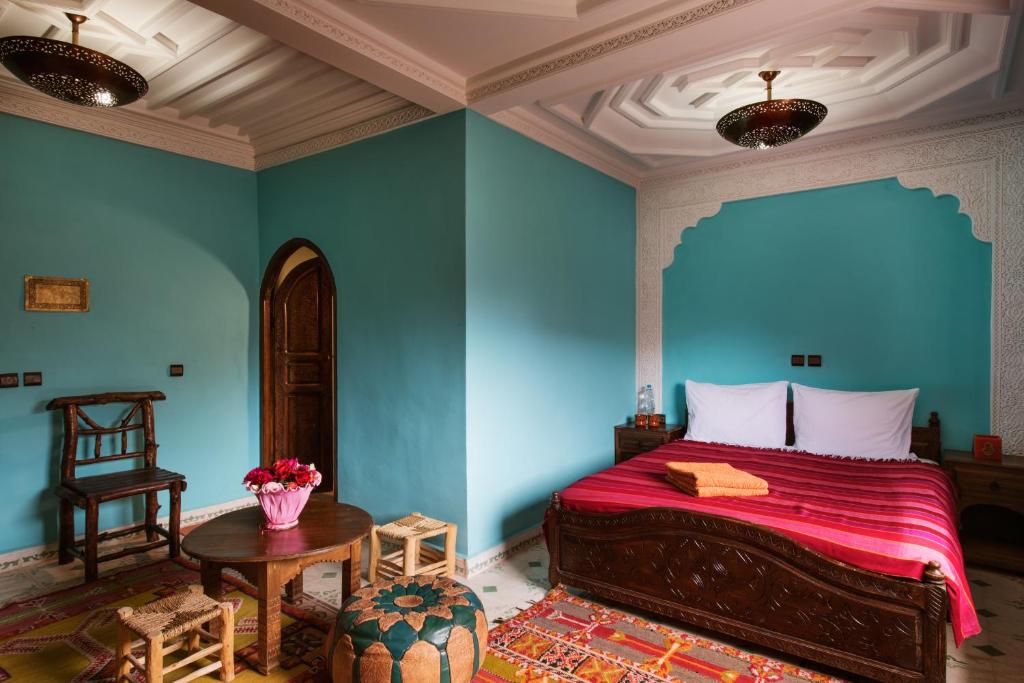 a bedroom with blue walls and a bed and a table at Imlil Lodge in Imlil
