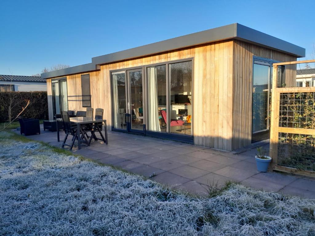 a house with a patio with a table and chairs at Luxe 5 persoons bungalow op rustig vakantiepark nabij Leeuwarden in Dronrijp