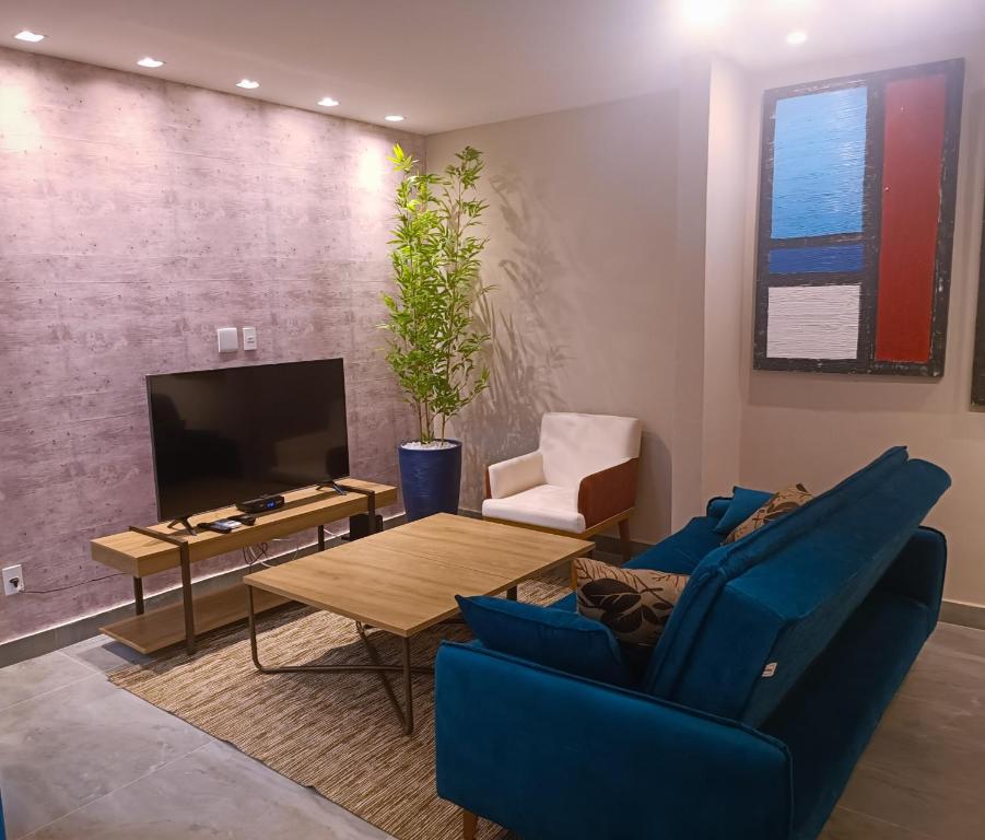 sala de estar con sofá azul, mesa y TV en PIRAGIBE FROTA AGUIAR, en Río de Janeiro