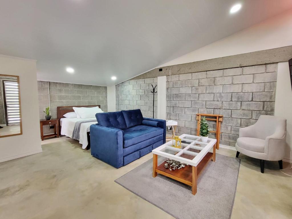 a living room with a blue couch and a bed at Casa del Café - Loft in Heredia
