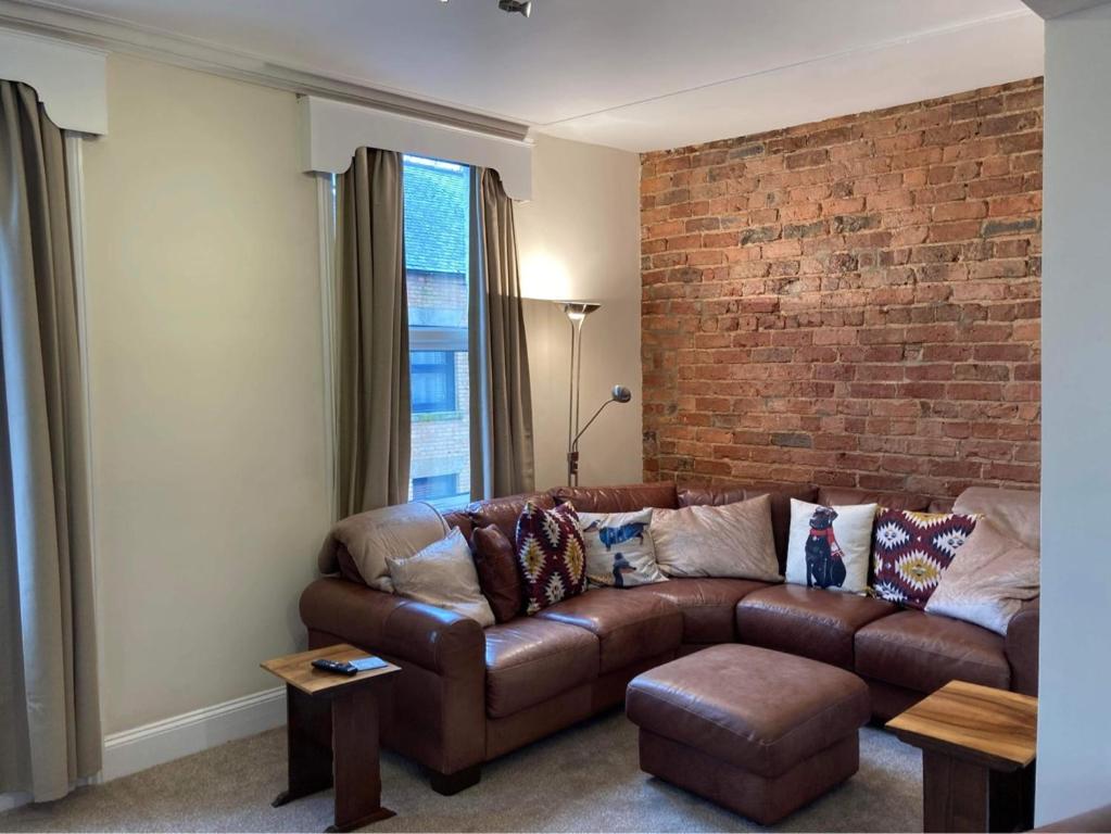 a living room with a brown couch and a brick wall at Hope Corner in Filey