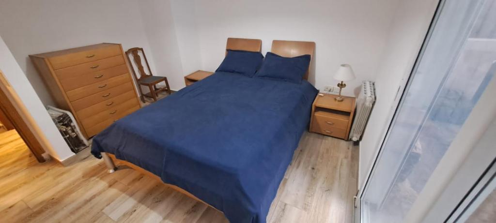 1 dormitorio con 1 cama con sábanas azules y suelo de madera en casa regina en Mar del Plata