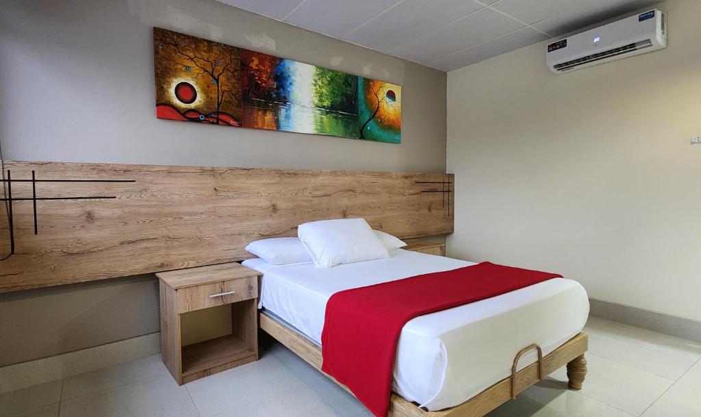 1 dormitorio con 1 cama y una pintura en la pared en Hotel Murali - Cerca del Aeropuerto de Guayaquil, en Guayaquil