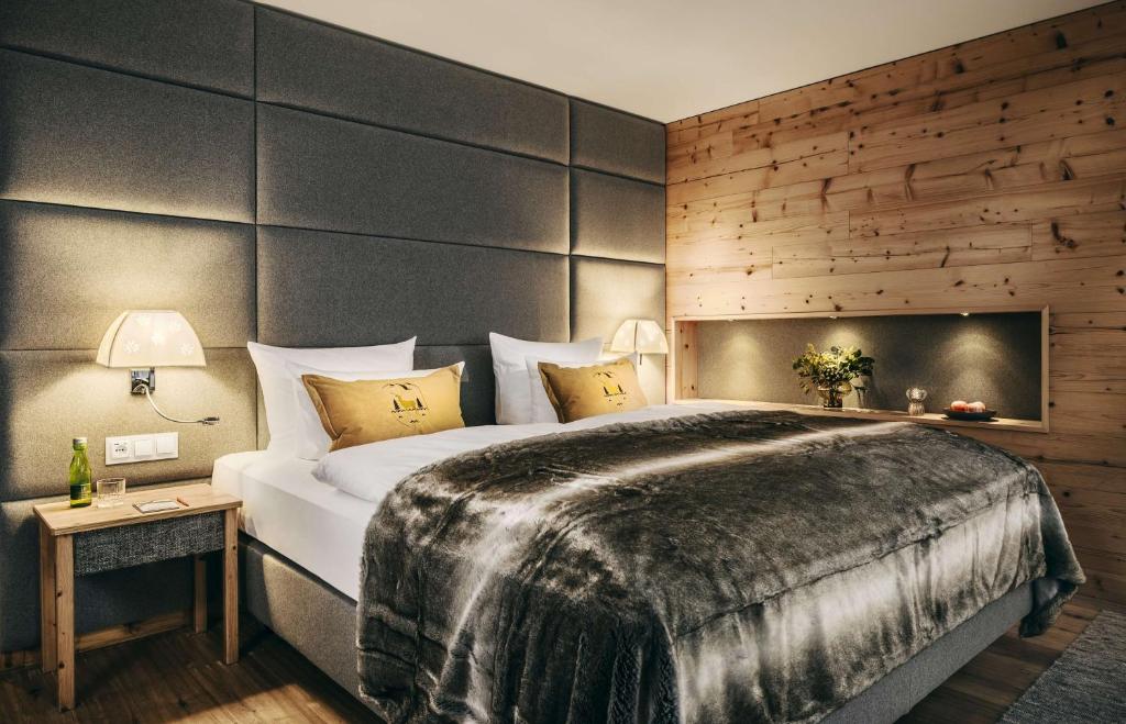 a bedroom with a large bed and a wooden wall at Grand Tirolia Kitzbühel - Member of Hommage Luxury Hotels Collection in Kitzbühel