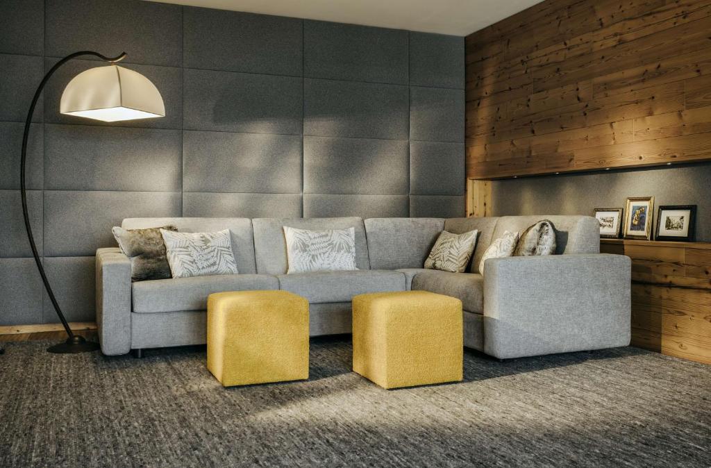 a living room with a couch and two yellow stools at Grand Tirolia Kitzbühel - Member of Hommage Luxury Hotels Collection in Kitzbühel