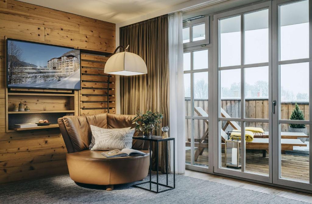 a living room with a chair and a television at Grand Tirolia Kitzbühel - Member of Hommage Luxury Hotels Collection in Kitzbühel