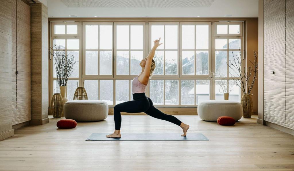 a woman doing a yoga pose in a room with a window at Grand Tirolia Kitzbühel - Member of Hommage Luxury Hotels Collection in Kitzbühel