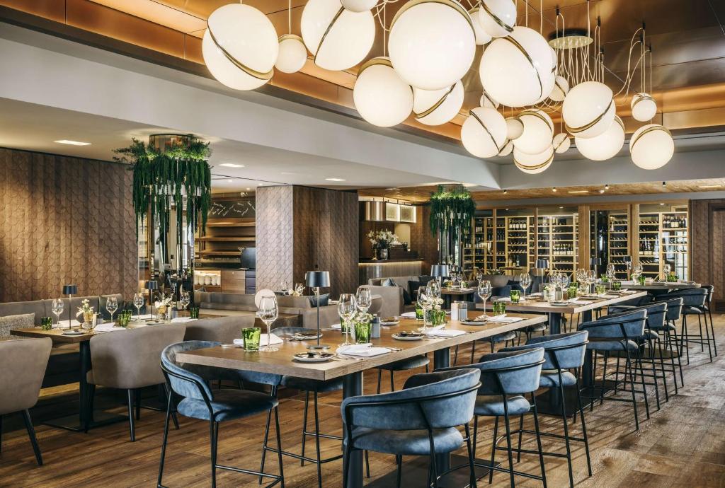 a restaurant with long tables and chairs and a large chandelier at Grand Tirolia Kitzbühel - Member of Hommage Luxury Hotels Collection in Kitzbühel