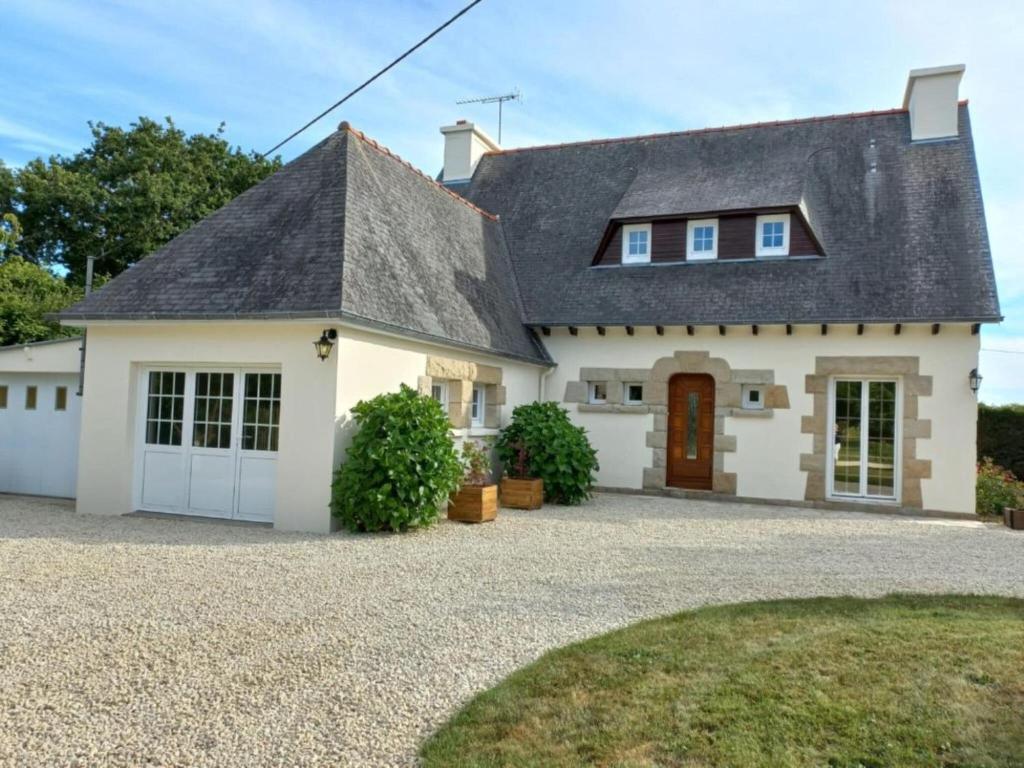 a white house with a black roof and a driveway at Large holiday home with garden in Brittany in Hénansal